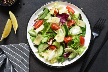 Green salad with tomatoes and fried bread on a dark concrete background. Top view with place for text.
