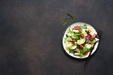 Green salad with tomatoes and fried bread on a dark concrete background. Top view with place for text.
