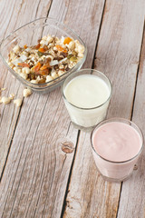 Two glasses of healthy strawberry and classic yogurt with oats on wooden table. healthy breakfast. close up with copy space. homemade fresh yogurts with cereals , two glasses of dairy product.