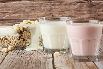 Two glasses of healthy strawberry and classic yogurt with oats on wooden table. healthy breakfast. close up with copy space. homemade fresh yogurts with cereals , two glasses of dairy product.