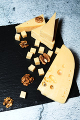 Pieces of cheese with walnuts on a dark background.
