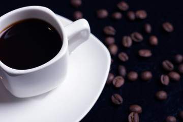 Coffee cup and coffee beans on black background. Top view, place for text