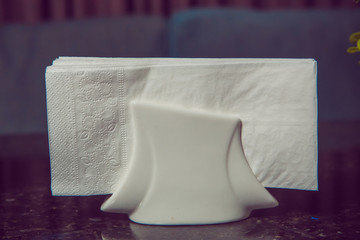 White napkins in a metal napkin holder, spices salt and pepper on a woodeglass table, panoramic view. toothpick . A table in a cafe or restaurant.