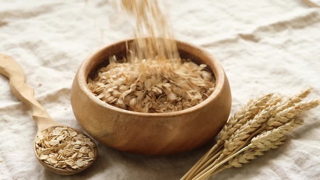Slow motion of Oats, oat flakes, rolled oats falling in bowl. Concept of healthy eating, healthy lifestyle, dieting, dietary fiber vegan vegetarian food