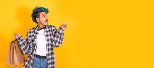 young girl with shopping bags in color background pointing