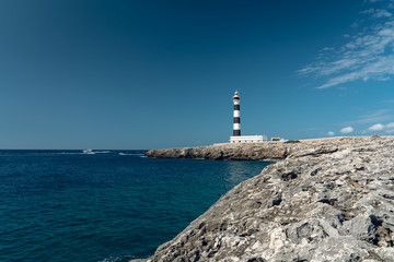 Majestic Artrutx lighthouse on the beautiful rocky coastline of western Menorca island, Spain