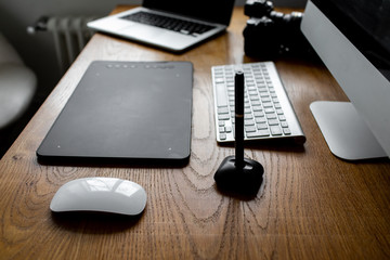 Photographer drawing and retouching image on laptop computer, using a digital tablet and stylus pen. Workspace at home