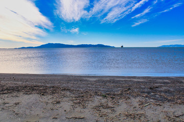 Seascape view over Tuscany beach famous landmark, under a stormy sky with heavy grey clouds and warm sun rays passing through, Italy