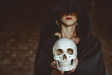 a witch holds a human skull