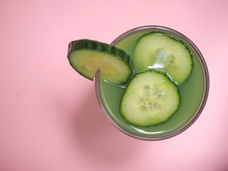 Top view of organic cucumber juice on pink background