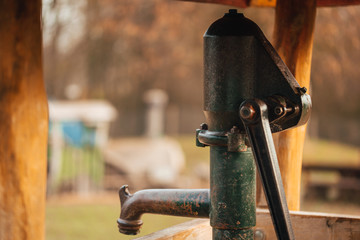 Old and rusty water pump on a playground for children.