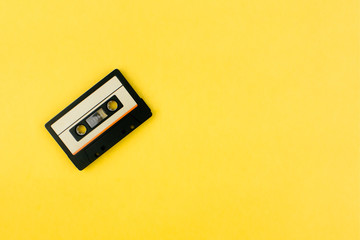Audio cassette tape flat lay on colorful yellow background top view with copy space. Creative fashion design in minimal retro 80-s style. Music, radio, dj concept. Web banner template. Stock photo.