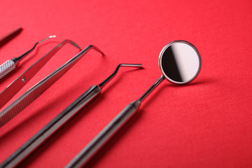 Side view of dentist metal tools on red background