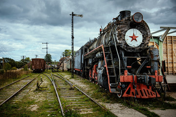 Obraz premium Stara lokomotywa pociągu parowego z dramatycznym tle chmur.