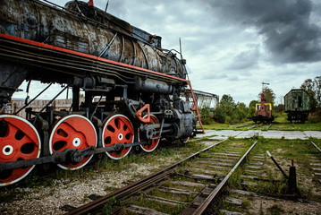 Old steam train locomotive with dramatic cloud background.