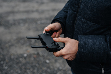 A young man holds a remote control for controlling a copter.
