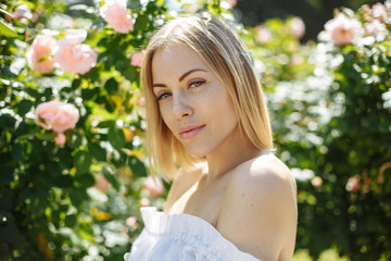 girl in a white dress in the garden of tender pink roses