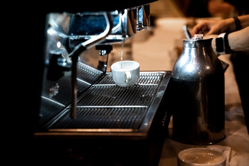 Woman preparing an espresso coffee at a coffee grinder in a restaurant