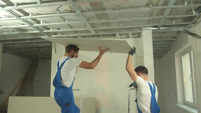 Repairmen in uniform install the panel on the ceiling