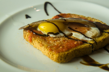 slice of bread with quail egg, anchovy and vinegar cream