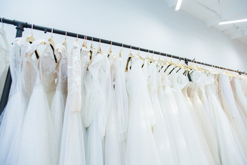 Horizontal low angle no people shot of wedding gowns on clothes rails in modern bridal dress-making studio