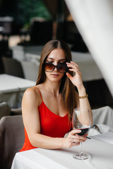 Beautiful young girl sits and drinks wine on the veranda of a beautiful house. Holiday.
