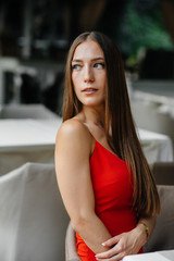 A beautiful young girl is sitting on the veranda of a beautiful house. Relaxation.