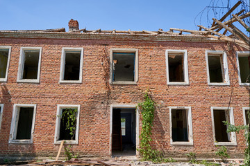 Demolition of an old house with brick walls against a blue sky