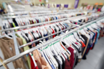 Blurred background image of a store with rows of clothes for women. Template for text.