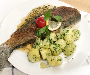 Classic prepared whole lake trout with skin "Müllerin" Art. Fried in the pan and with parsley potatoes and lemon side dishes.