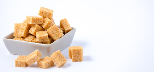 Brown sugar in a square cup on a white background, healthy sugar is used for cooking or desserts.