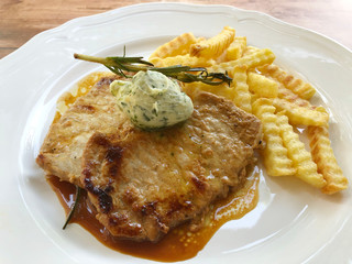 Juicy minute steaks for summer and barbecue, with french fries, herb butter and herbs.
