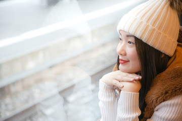 An Asian woman is sitting happily looking at the natural view from the window on the train and traveling on a vacation in Switzerland and planning a train trip.