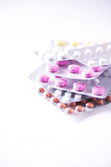 Multicolored pills in blisters over white background. Copy space. Bunch of drugs, cold flu treatment. Coronavirus Covid-19.