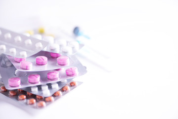 Multicolored pills in blisters over white background. Copy space. Bunch of drugs, cold flu treatment. Coronavirus Covid-19.