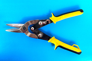 Old scissors for metal. Tool for cutting sheet metal on a blue background.