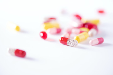 Multicolor tablets and pills over white background with copy space. Assorted various medicine capsules, pills and drugs. Health care