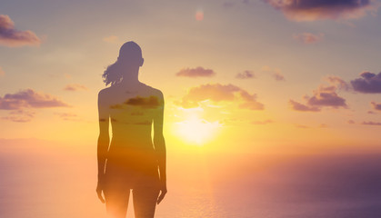 Silhouette of thoughtful woman standing in the sunset. Double exposure 