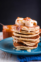Delicious and lush pancakes with fresh fruits and berries, poured with salted caramel. Mint, tea, orange juice, milk on the table.