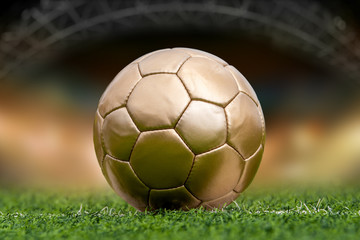 Closeup golden soccer ball on green grass