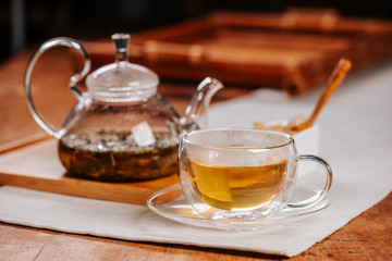 Cup of hot tea with rock sugar, dry tea leaves served in thermo glass tea cup