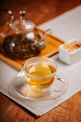 Cup of hot tea with rock sugar, dry tea leaves served in thermo glass tea cup