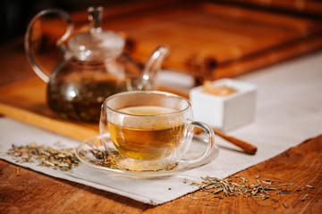 Cup of hot tea with rock sugar, dry tea leaves served in thermo glass tea cup