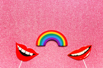 Concept of relationship between women, flatlay false photo stand props lips rainbow on pink shiny background copy space