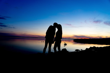 silhouette of Young couple holding hands and kissing next to lake balaton Hungary