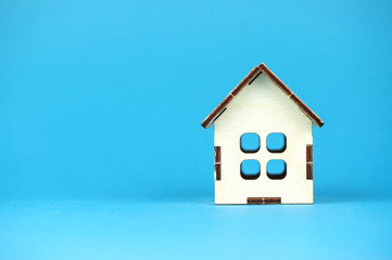 wooden house on a blue background, a place for text, the concept of buying a home