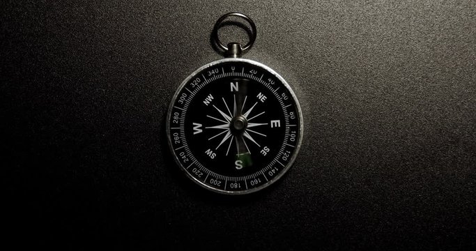 Disorientated spinning compass against steel background closeup footage