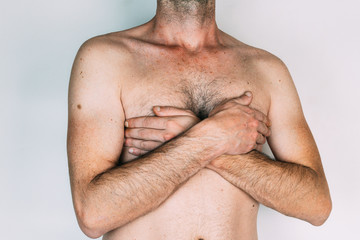 Caucasian man without shirt with hands on chest, isolated on gray background
