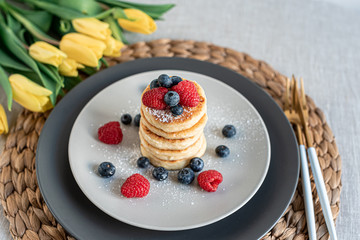 Cottage cheese pancakes with berries, healthy breakfast, yellows tulips, spring, woman's day