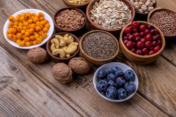Different superfoods set, seeds, nuts,  grains, cranberries, dried apricots, sea buckthorn, blueberries, oatmeal. Vegetarian healthy diet concept.